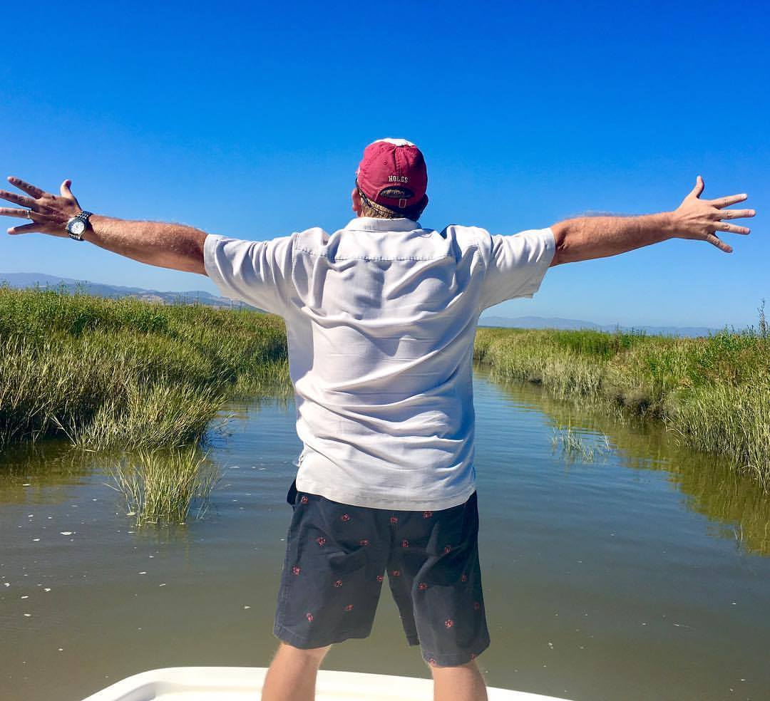 A customer relaxing on the front of the boat on a wetlands tour in the Napa-Sonoma Marshes.